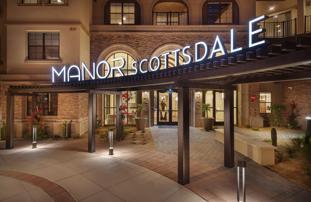Illuminated Manor Scottsdale signage above the lobby entrance on N. Scottsdale Road at night